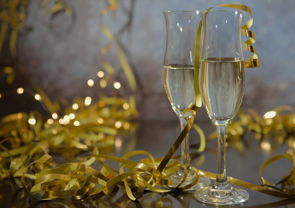 Two champagne glasses with golden ribbon streamers surrounded by festive decorations — perfect setup for bachelorette party entertainment, games, and celebration.

