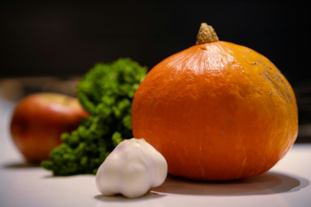 Fresh autumn food produce including pumpkin, garlic, apple, and parsley — perfect ingredients for seasonal cooking and hearty fall recipes.