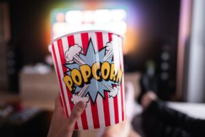 Hand holding a colorful popcorn bucket during a cozy lazy weekend movie marathon.