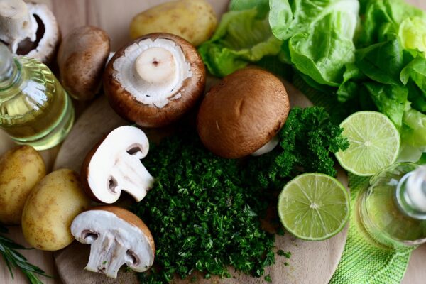Fresh food ingredients including mushrooms, potatoes, lime, lettuce, parsley, and olive oil — perfect for cooking with seasonal produce.