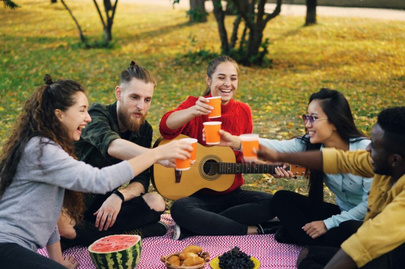 osoby siedzące na kocu w parku
