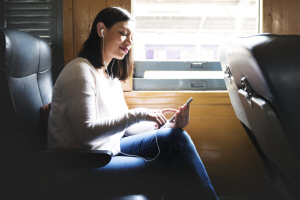 asian-woman-riding-train-scaled-listening-music